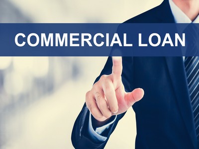 A man pointing to the words commercial loan on his finger.